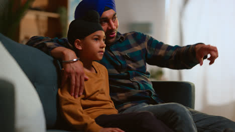 Sikh-Father-And-Son-Wearing-Turbans-Sitting-On-Sofa-At-Home-Talking-Together-Shot-In-Real-Time